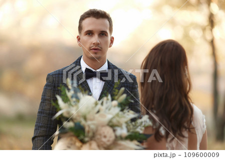 portrait of bride in white wedding dress and groom standing outdoor on natural background 109600009