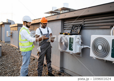Multicultural males repairing air conditioner using tablet 109601024