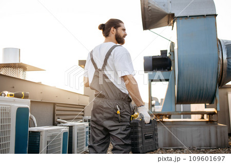 Master with tool case standing on roof of industrial plant 109601697