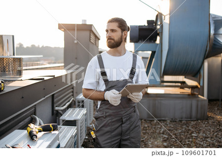 Construction man using tablet while working on rooftop 109601701