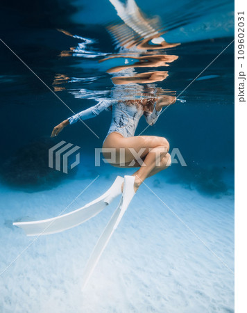Woman in wetsuit with fins in transparent clear ocean on Hawaii islands. Freediver girl underwater 109602031