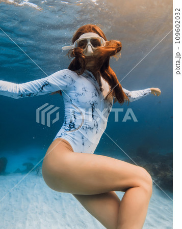 Gorgeous freediver woman posing underwater. Freediving with sexy woman in blue ocean and amazing warm sun rays 109602032