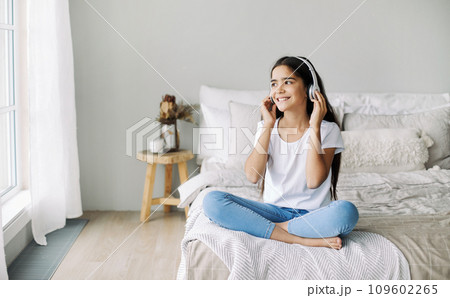 Pretty pre-teen girl listen music through wireless headphones 109602265