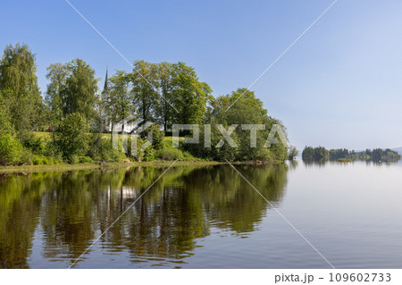 Summer view of Kvam Church in Nord-Fron Norway through trees by Snasavatnet lake 109602733
