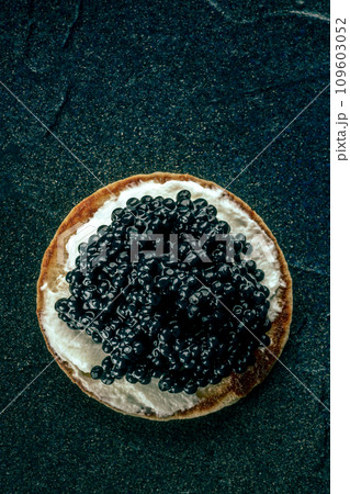 A blini with caviar and cream cheese, shot from the top on black A blini with caviar and cream cheese, shot from the top on black 109603052
