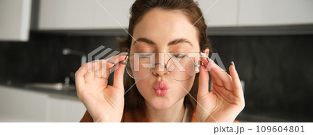Close up portrait of happy, carefree young woman in her new glasses, showing her eyewear, laughing and smiling, posing in kitchen Close up portrait of happy, carefree young woman in her new glasses, showing her eyewear, laughing and smiling, posing in kitchen 109604801