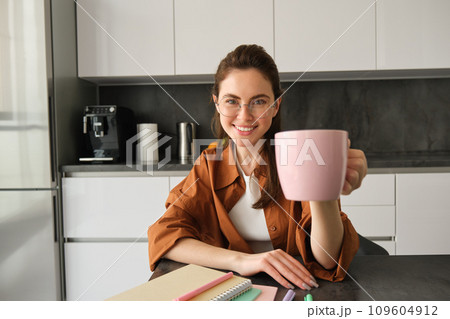 Portrait of stylish young woman, student shares her cup of coffee, gives you mug, smiling and looking happy Portrait of stylish young woman, student shares her cup of coffee, gives you mug, smiling and looking happy 109604912