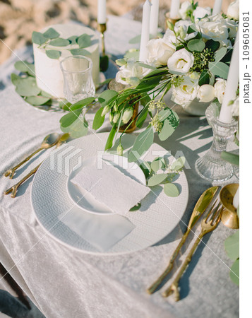 Elegant table setting with a paper card decorated with eucalyptus branches. Romantic table with paper invitation card. Wedding Mockup. Elegant table setting with a paper card decorated with eucalyptus branches. Romantic table with paper invitation card. Wedding Mockup. 109605081