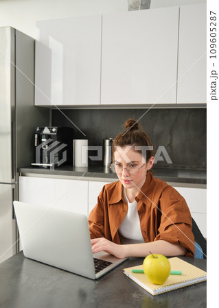 Vertical shot of young freelancer, woman working from home, typing on laptop, looking at screen Vertical shot of young freelancer, woman working from home, typing on laptop, looking at screen 109605287
