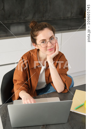 Vertical shot of woman working from home, business owner using laptop, browsing social media on computer, wearing glasses 109605745