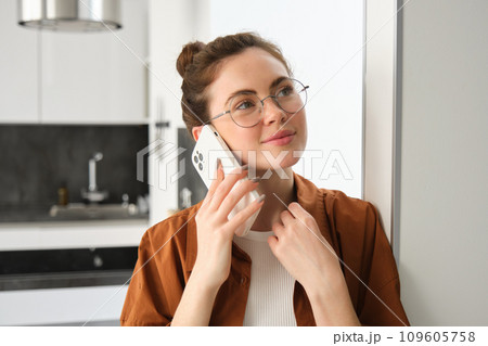 Portrait of happy woman at home, answers phone call, talking on mobile, holding smartphone and smiling 109605758