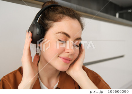 Close up shot of modern stylish woman in headphones, relaxes while listens to music in wireless earphones 109606090