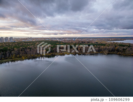 Autumn forest on lake shore at sunset and city on horizon, aerial view Autumn forest on lake shore at sunset and city on horizon, aerial view 109606299