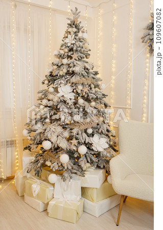 Christmas tree with in artificial snow, with festive decorations, white xmas glittering baubles, balls, shiny flower ornaments. Garland with gold lights Illuminate on backdrop. New year 2025 holidays. Christmas tree with in artificial snow, with festive decorations, white xmas glittering baubles, balls, shiny flower ornaments. Garland with gold lights Illuminate on backdrop. New year 2025 holidays. 109607082