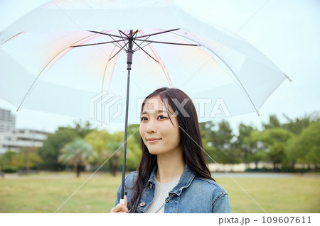 雨の中で公園で傘をさして散歩をする女性 雨の中で公園で傘をさして散歩をする女性 109607611