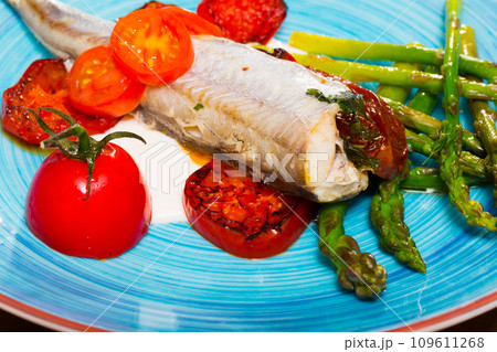 Baked fish poutassou with asparagus, dried tomatoes and creamy-garlic sauce 109611268