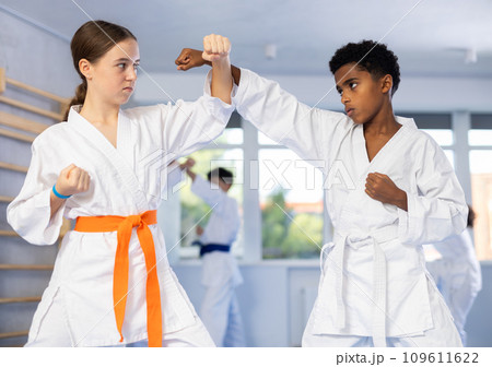 African teenager practicing punches in sparring with girl at martial arts training African teenager practicing punches in sparring with girl at martial arts training 109611622