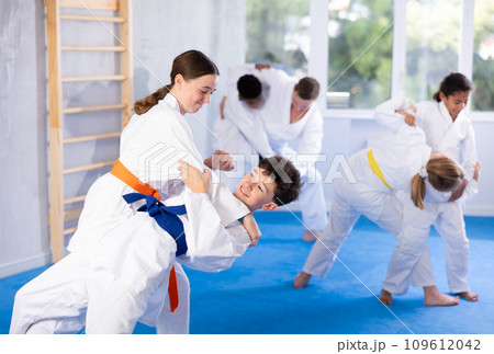 Teenage girl practicing fighting techniques during martial arts sparring with boy 109612042
