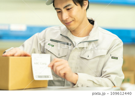 出荷前に外装箱にラベルを貼る男性作業員 109612440