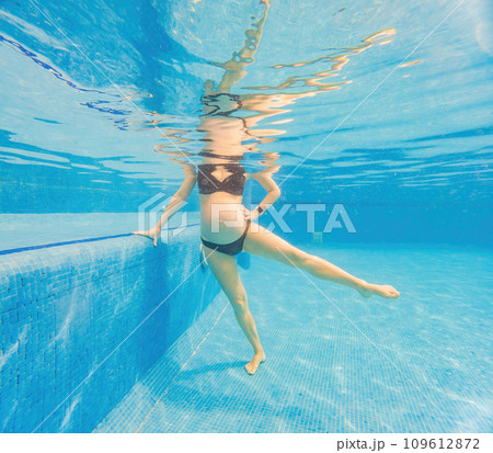 Embracing aquatic fitness, a pregnant woman demonstrates strength and serenity in underwater aerobics, creating a serene and empowering image in the pool 109612872