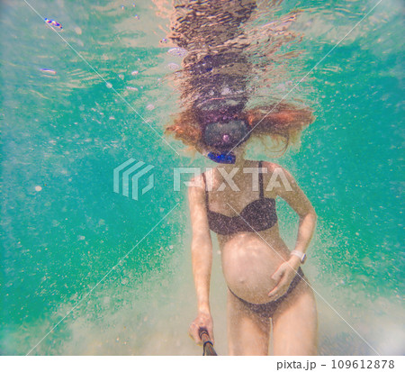 In an ethereal underwater scene, a pregnant woman gracefully floats, embodying the beauty of maternity beneath the tranquil surface of the sea 109612878