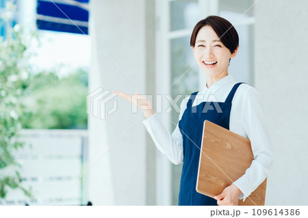 カフェの店内に案内する女性 109614386