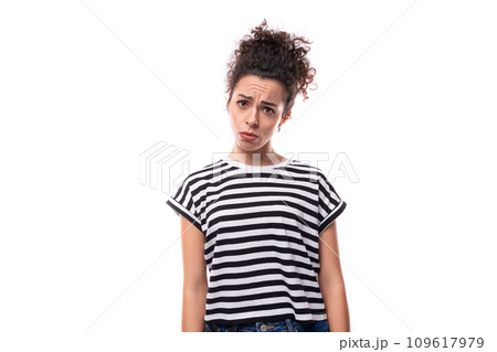 young curly brunette woman in a striped t-shirt on a white background with copy space 109617979