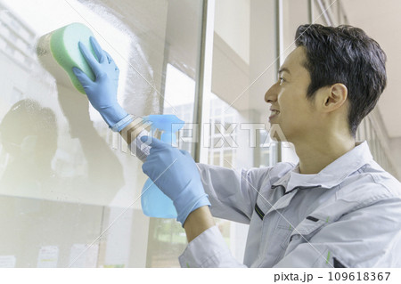 オフィスで窓の掃除をする男性清掃員　撮影協力：有明教育芸術短期大学 109618367
