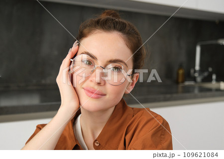 Portrait of gorgeous young woman in glasses, with happy smile, looking cute and tender, concept of modern people lifestyle Portrait of gorgeous young woman in glasses, with happy smile, looking cute and tender, concept of modern people lifestyle 109621084