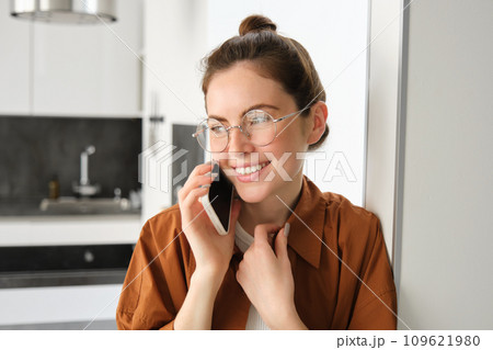 Portrait of happy smiling young woman at home, talking on mobile phone, calling friend and having nice conversation, answer telephone Portrait of happy smiling young woman at home, talking on mobile phone, calling friend and having nice conversation, answer telephone 109621980