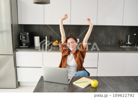 Portrait of cheerful young woman, student stretches her hands with pleased face, accomplish goal, finish working on project, using laptop and smiling pleased Portrait of cheerful young woman, student stretches her hands with pleased face, accomplish goal, finish working on project, using laptop and smiling pleased 109622792