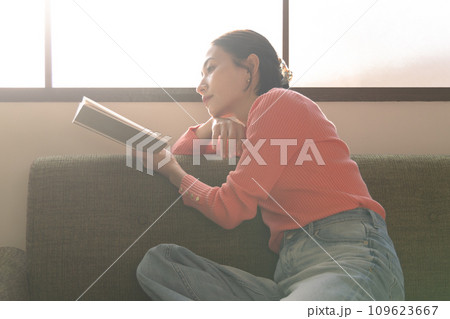リビングでソファに座りリラックスして本を読む女性 109623667