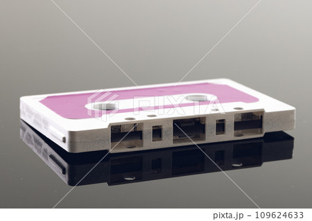 Close up of white and pink cassette tape on grey background with reflection 109624633