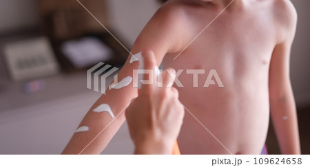 Mother applying sunscreen to baby skin closeup 109624658