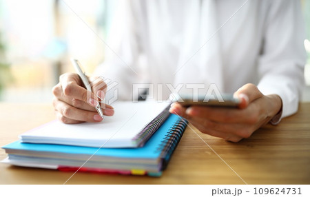 Closeup of freelancer hands with mobile phone working on finance Closeup of freelancer hands with mobile phone working on finance 109624731