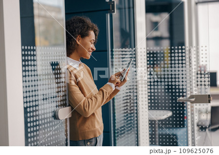 Stylish female freelancer is using mobile phone standing in coworking during break time Stylish female freelancer is using mobile phone standing in coworking during break time 109625076
