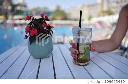 Female hand holding alcoholic cocktail with ice mojito closeup 109625410