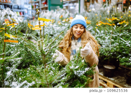 Beautiful young woman buys a Christmas tree at the fair. New Year's holiday concept 109625536