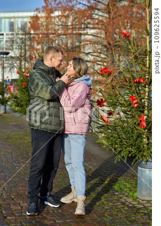 Portrait of young attractive people, lovely couple enjoying cozy atmosphere on fair in Christmas Eve. Spending time together. Concept of national traditions, winter holidays, fashion, festivities Portrait of young attractive people, lovely couple enjoying cozy atmosphere on fair in Christmas Eve. Spending time together. Concept of national traditions, winter holidays, fashion, festivities 109625594