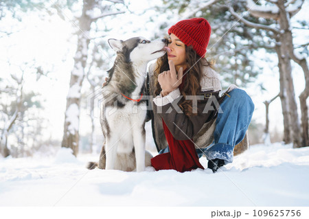Young woman walking her dog in winter and both explore the snow together in playful mood. Friendship Young woman walking her dog in winter and both explore the snow together in playful mood. Friendship 109625756