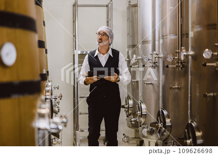 Winemaker professional working in modern large winery factory liquor alcohol drinks industry quality control and fermentation monitor vintage color tone 109626698