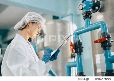 Drinking water factory purification process. Hygiene factory worker female monitor checking valve and water pipe production flow control. 109627099