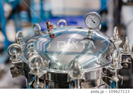 Closeup Pressure Tank Cap Locked. Stainless Steel Sanitary Round Tank Manway Manhole Door Cover Lock With Pressure Gauge In Industry Factory. Closeup Pressure Tank Cap Locked. Stainless Steel Sanitary Round Tank Manway Manhole Door Cover Lock With Pressure Gauge In Industry Factory. 109627113