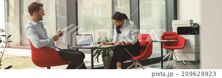 Two diverse business colleagues working together on project sitting in modern meeting room 109628923