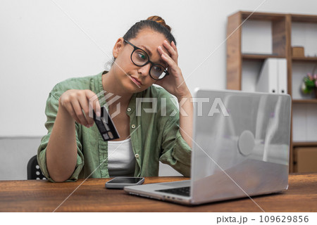 A woman, donning glasses, expertly manages online payments and shopping with her credit card and laptop. A woman, donning glasses, expertly manages online payments and shopping with her credit card and laptop. 109629856