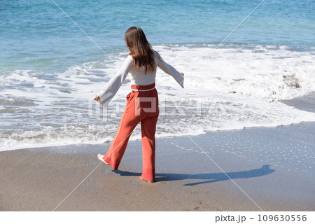 砂浜を素足で歩く女性 109630556