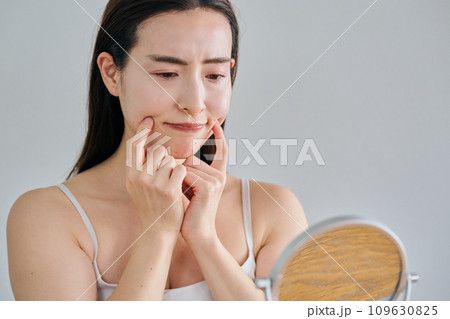 鏡を見ながら肌のシワを気にする30代女性 109630825