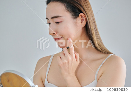 鏡を見ながら肌のシワを気にする30代女性 109630830