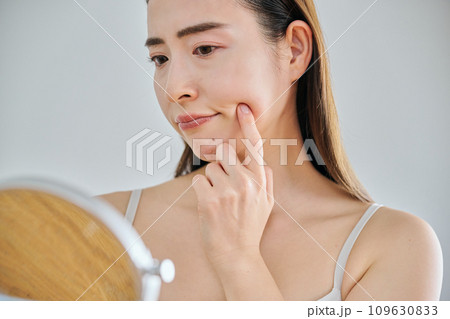 鏡を見ながら肌のシワを気にする30代女性 109630833