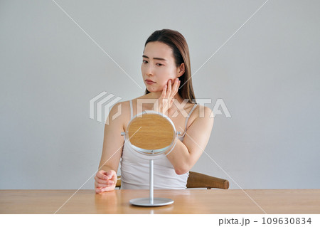 鏡を見ながら肌のシワを気にする30代女性 109630834